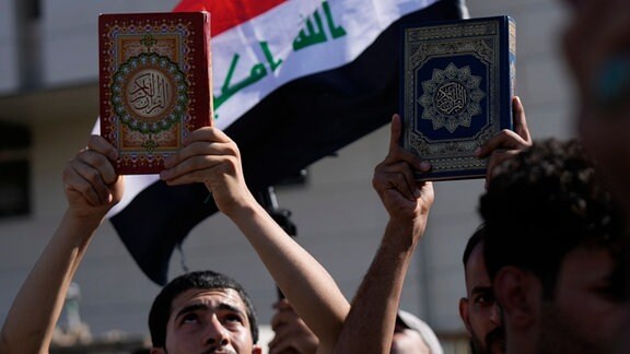 Anhänger des schiitischen Geistlichen Muqtada al-Sadr halten den Koran, das heilige Buch der Muslime, während einer Demonstration vor der schwedischen Botschaft in Reaktion auf die Koranverbrennung in Schweden hoch. 