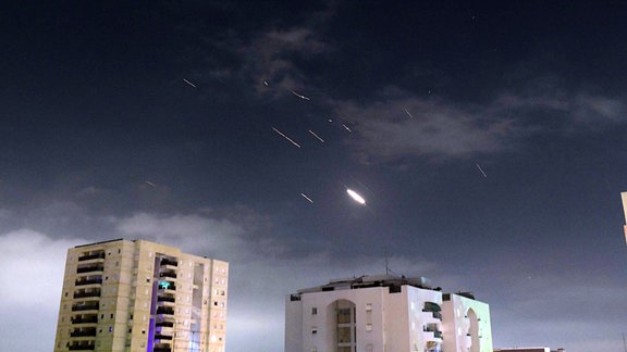 Flammen von Explosionen erscheinen am Himmel über Tel Aviv, während Israels Raketenabwehrsystem Raketen und Drohnen aus dem Iran abfängt. 