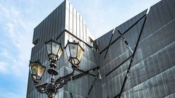 Blick auf das Jüdische Museum Berlin: Eine Glasfassade mit mehreren Furchen.