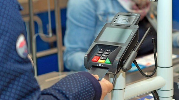 Ein Kundin zahlt mit einer Kreditkarte ihren Einkauf an einem Terminal für den bargeldlosen Zahlungsverkehr.