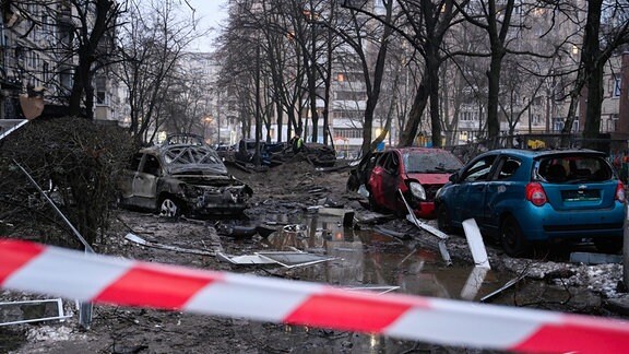 Absperrband vor beschädigten Autos nach einem Raketenangriff der russischen Armee.