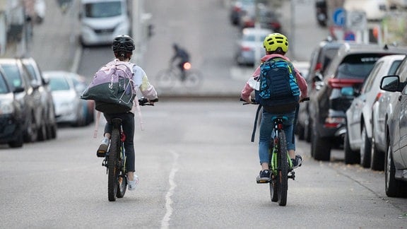 zwei Kinder fahren auf ihren Rädern eine Straße entlang