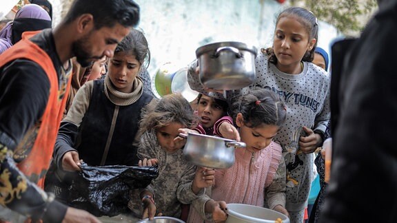Palästinenser erhalten von Freiwilligen gekochte Lebensmittel für Menschen, die aufgrund des israelischen Bombardements von Chan Junis nach Rafah geflohen sind.