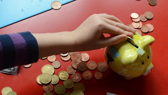 Ein fünfjähriger Junge steckt Euro-Münzen in sein Sparschwein, aufgenommen am 10.4.2012 in Berlin.