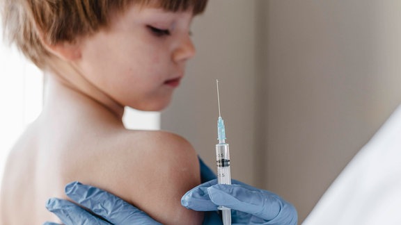 Arzt mit Handschuhen bei der Impfung eines kleinen Kindes