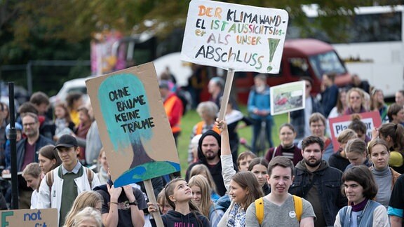 Teilnehmer des globalen Klimastreiks von Fridays for Future (FFF) stehen während einer Kundgebung mit Transparenten vor der Bühne.