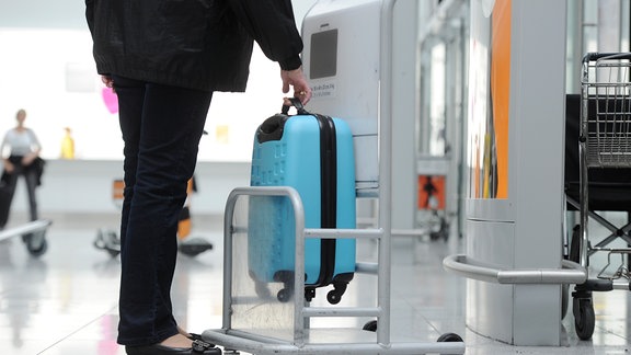 Ein blauer Koffer wird auf seine Größe als Handgepäck überprüft