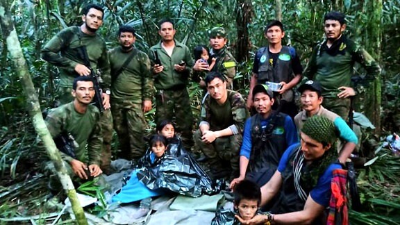 Auf diesem von der Pressestelle der kolumbianischen Streitkräfte veröffentlichten Foto posieren Soldaten und indigene Männer für ein Foto mit den vier Geschwistern, die nach einem tödlichen Flugzeugabsturz vermisst wurden, im Dschungel von Solano im kolumbianischen Bundesstaat Caqueta. 