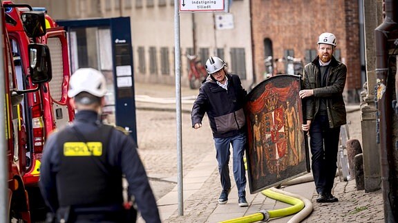 Menschen tragen historische Gemälde aus dem brennenden Gebäude,