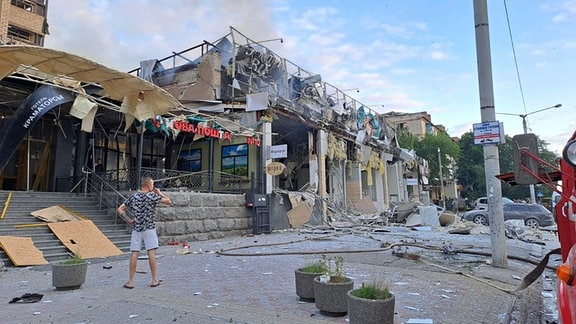 Ein Mann auf der Straße vor einem Restaurant RIA Pizza, das durch einen russischen Angriff zerstört wurde.