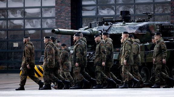 Soldaten marschieren an einem Leopard 2 A6 Kampfpanzer vorbei.