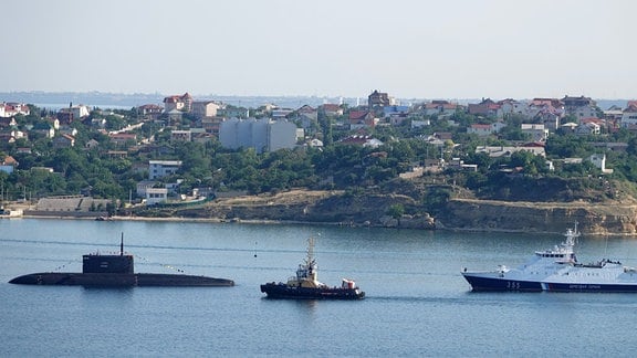 Ein U-Boot und Kriegsschiffe liegen vor Anker in der Hafenstadt der Krim