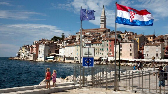 Fahnen der EU und der von Kroatien wehen an einer Hafeneinfahrt in Rovinj