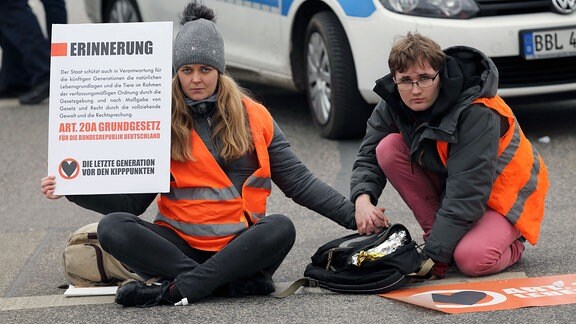 Klimaaktivisten der Gruppierung Letzte Generation blockieren mit angeklebten Händen den Straßenverkehr auf der Langen Brücke.