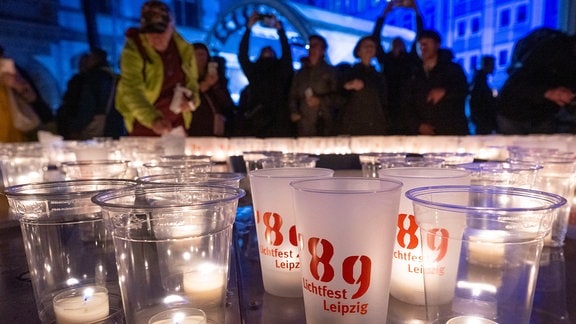 Bürgerinnen und Bürger gestalten im Hof der Nikolaikirche in Lepzig eine 89 aus Kerzen.