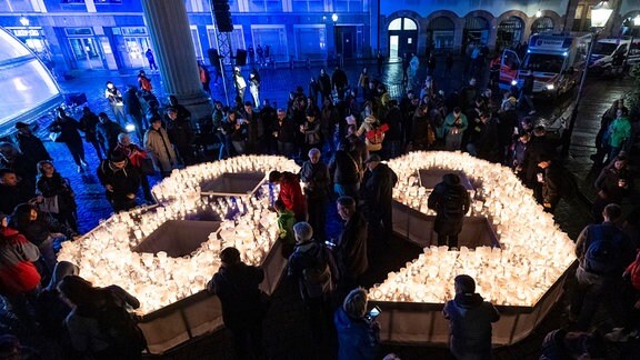 Bürgerinnen und Bürger gestalten im Hof der Nikolaikirche in Lepzig eine 89 aus Kerzen.