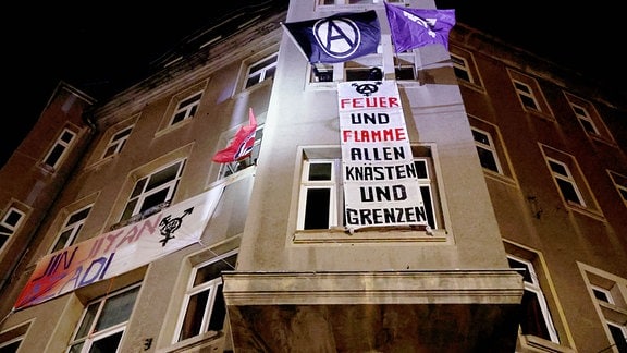 Linke Protestler hissen die Antifa-Fahne und ein Banner mit der Aufschrift "Feuer und Flamme allen Knästen und Grenzen" bei Protesten gegen das Urteil im Prozess gegen Lina E.