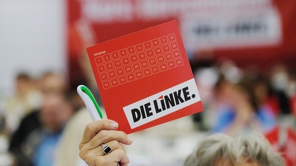 Eine Delegierte des Landesparteitages der Partei Die Linke in Sachsen hält 2021 ihre Stimmkarte in die Höhe. 