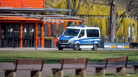 Ein Fahrzeug der Polizei fährt im Rotehornpark Streife während die Gastronomie geschlossen ist und Sitzbänke verlassen sind. 