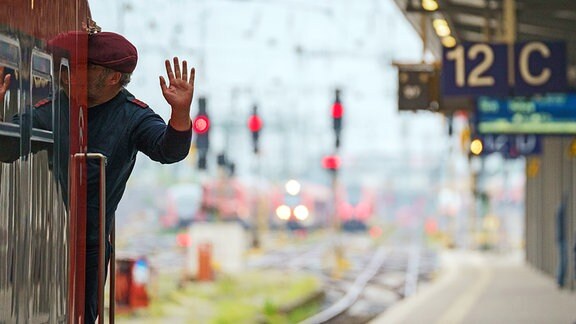 Ein Lokführer gibt im Hauptbahnhof, kurz vor Abfahrt des Zuges, ein Handzeichen.