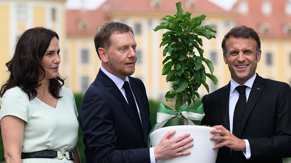 Emmanuel Macron (r), Präsident von Frankreich, Michael Kretschmer (CDU, 2.v.l), Ministerpräsident von Sachsen, und dessen Ehefrau Annett Hofmann (l) stehen vor dem Schloss Moritzburg.
