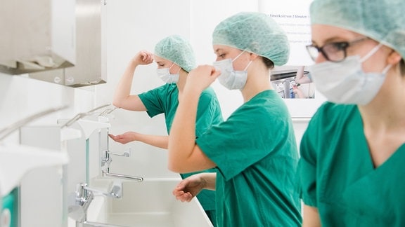 Medizinstudent*innen üben im "Skills Lab" der Medizinischen Hochschule Hannover (MHH) in der Waschstraße vor einem OP-Raum die hygienische Händereinigung (gestellte Szene).