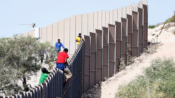 Migranten klettern über einen Zaun auf der Insel Lampedusa.
