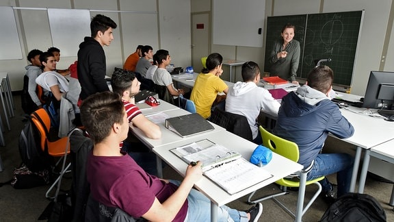 Eine Lehrerin unterrichtet eine Klasse mit minderjährigen Flüchtlingen. 