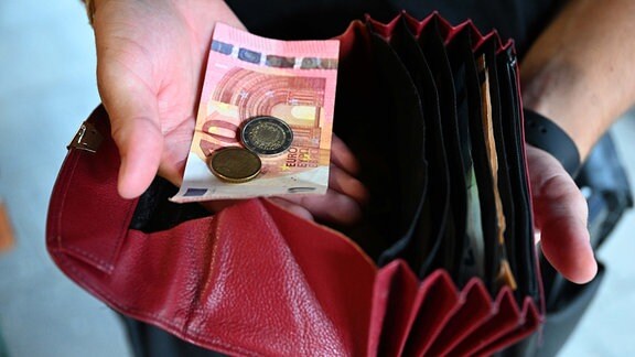 Ein Kellner eines Restaurants hält einen Geldbeutel in der Hand, während er in der anderen Hand Geld hält.