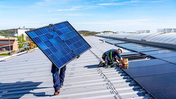 Montage von Solarmodulen auf dem Dach eines Gewerbebetriebs.