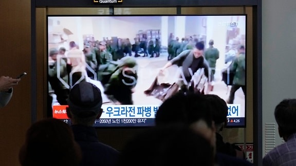 In einer Nachrichtensendung auf einem Fernsehbildschirm an einem Bahnhof sind Soldaten zu sehen, die vermutlich aus Nordkorea stammen.