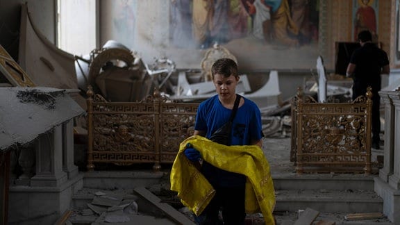 Ein Junge hilft bei der Bergung von Gegenständen in der Verklärungskathedrale Odessa, die bei Raketenangriffen schwer beschädigt wurde.