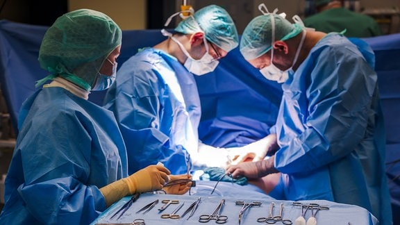Ärzte und OP-Personal stehen während einer Operation am OP-Tisch.