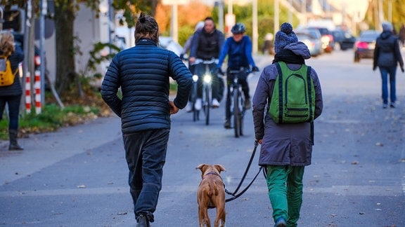 Radler und Spaziergänger in warmer Übergangskleidung, unterwegs in der Stadt