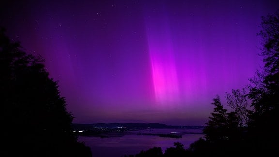 Polarlichter (Aurora borealis) leuchten am nächtlichen Himmel über dem Kochelsee. 