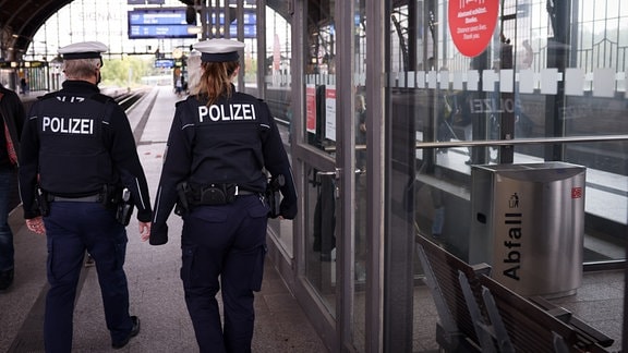 Polizisten gehen am Rande eines Pressetermins über den Bahnsteig am Bahnhof Dammtor.