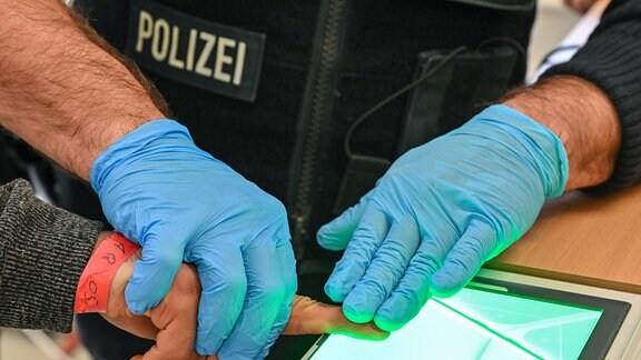 Ein Beamter der Bundespolizei nimmt den Fingerabdruck eines Migranten in der neu eingerichteten zentralen Bearbeitungstelle der Bundespolizei und des Bundesamtes für Migration und Flüchtlinge (BAMF) auf.