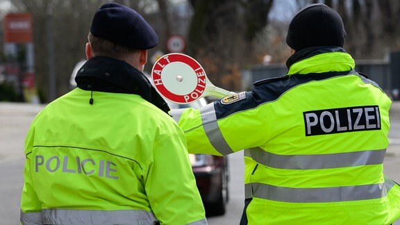 Ein Polizist aus Tschechien und ein Bundespolizist winken nahe dem Dreiländereck von Deutschland, Polen und Tschechien ein Auto zu Kontrolle heraus.