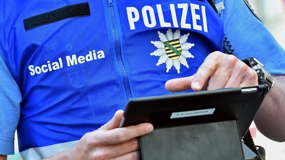 Beamte aus dem Social Media Team der Polizei sind bei einer Großveranstaltung im Zentrum von Leipzig (Sachsen) mit einem Tablet unterwegs.