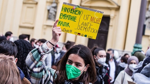 Eine junge Frau mit einem Schild zum Thema Nahostkonflikt