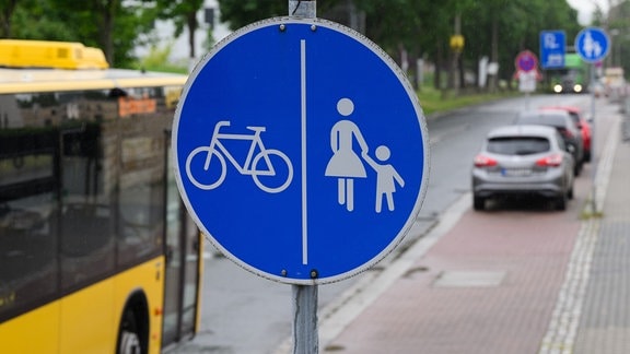 Ein Schild für einen getrennten Rad- und Gehweg steht vor dem Ende eines Radweges und dem Beginn der Zone in der das Parken auf dem halben Gehweg erlaubt ist.