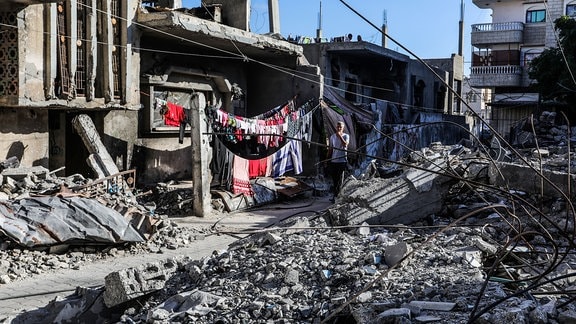 Ein vertriebener Palästinenser aus der Stadt Rafah läuft auf der Flucht vor den Kämpfen neben einem von israelischen Kampfflugzeugen zerstörten Gebäude.