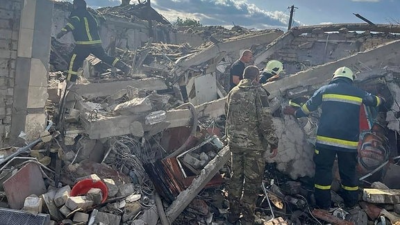 Einsatzkräfte auf den Trümmern eines komplett zerstörten Gebäudes.