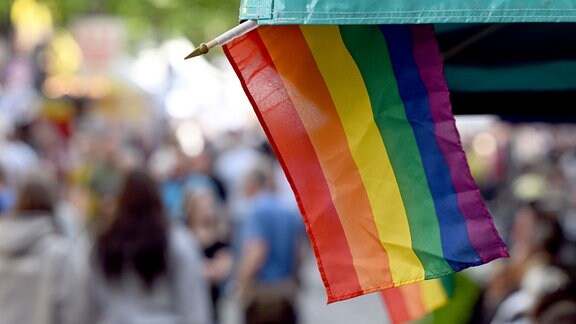 Regenbogenflaggen sind an einem Marktstand angebracht.