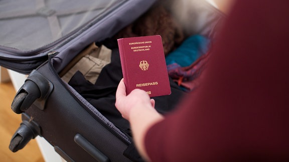 Ein Reisepass wird in einen Koffer gepackt.