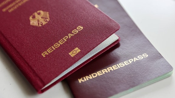 Ein deutscher Reisepass und Kinderreisepass liegen auf einem Tisch.