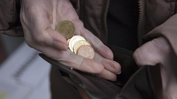 In der Hand einer älteren Person liegt Kleingeld.