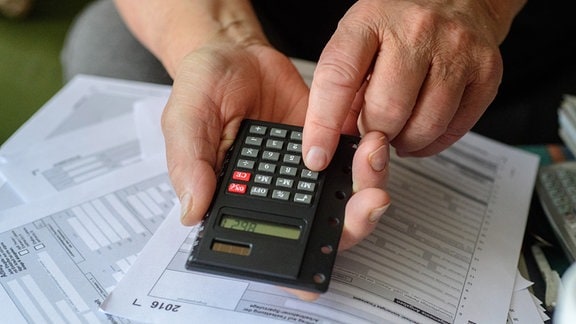 Ein Rentner tippt angesichts der fälligen Steuererklärung in seinen Taschenrechner