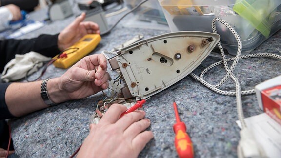 Ein Mann repariert ein Bügeleisen. 