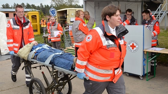 Rettungssanitäter bringen  bei der Notfallübung einen Verletzten zur Behandlung.
